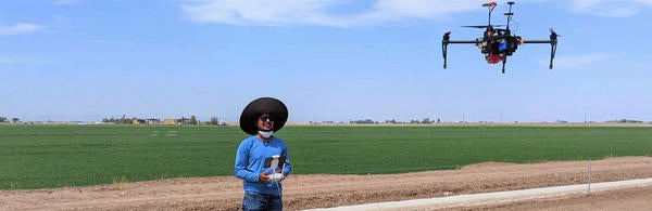 Amir Haghverdi Lab student flying a drone in a field