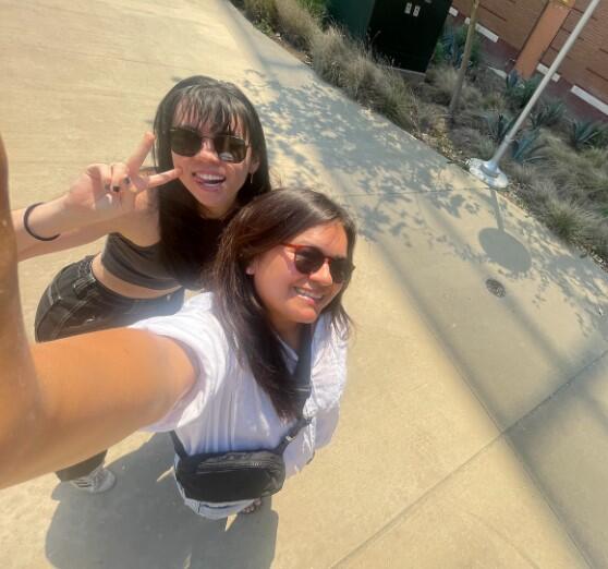 Two people taking a selfie, one holding up a peace sign